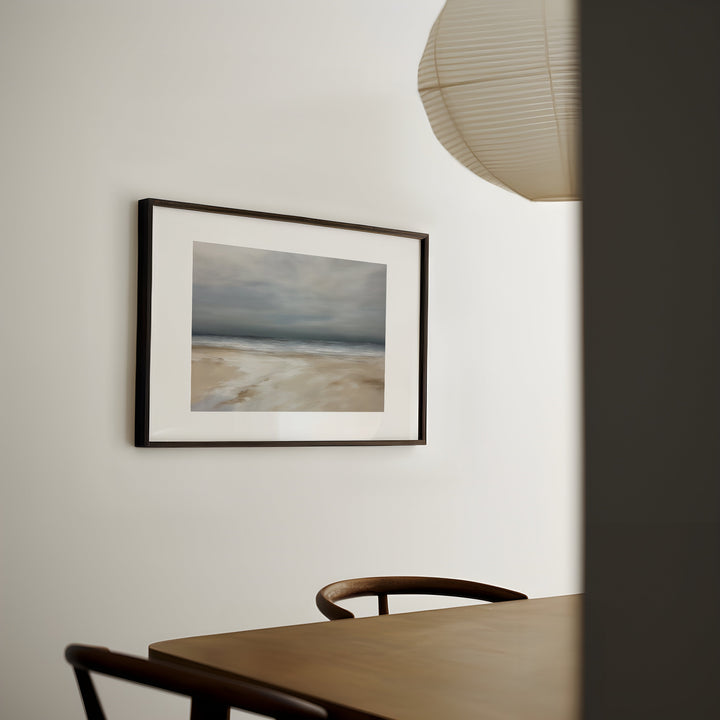 Framed artwork on a wall above a wooden table with chairs.